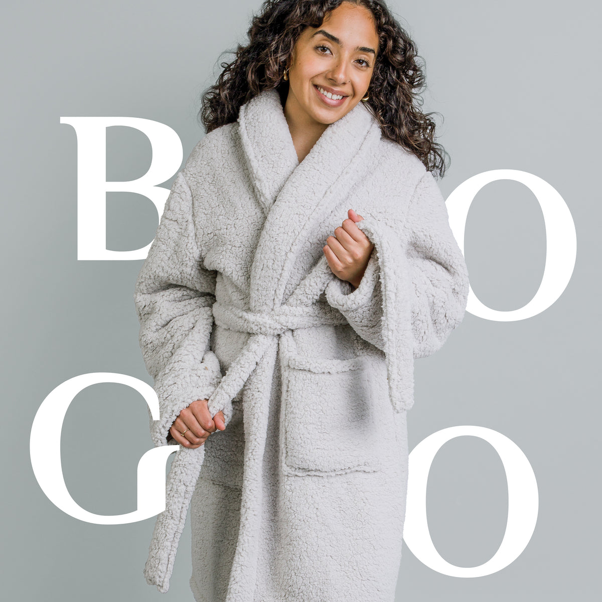 Image of a woman smiling, wearing a Sunday Morning Robe with BOGO spelled in white letters behind her