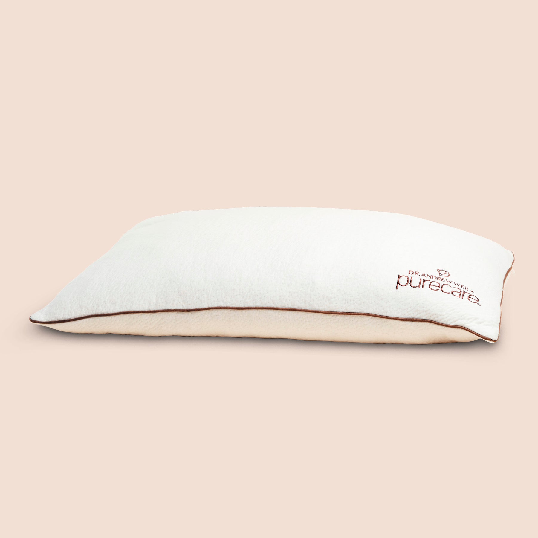 Image of Perfect Kapok Pillow on light pink background with Dr. Andrew Weil + Purecare logo in bottom right corner of pillow
