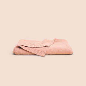 Image of a neatly folded Pink Sandstone Wave Coverlet with one corner folded over