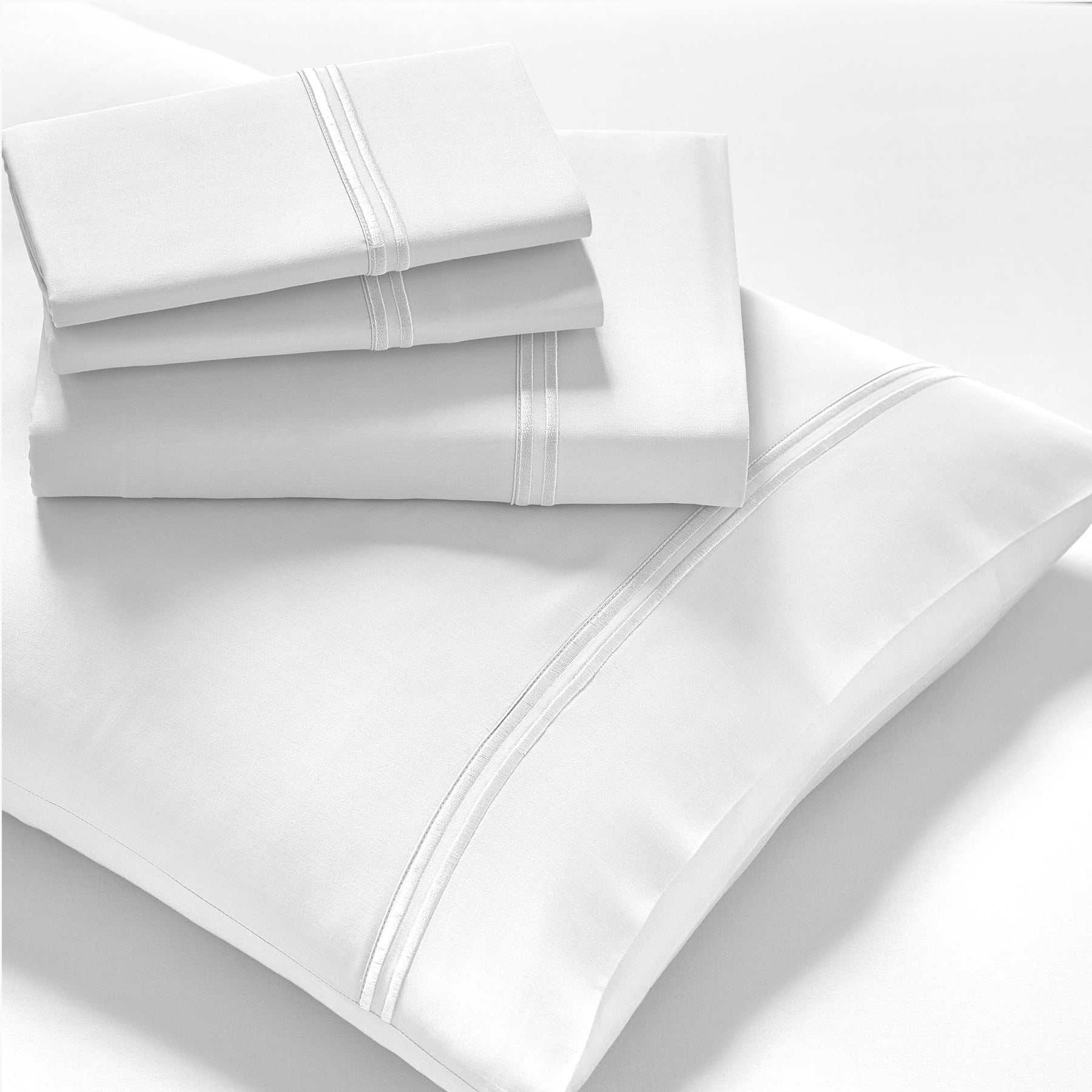 Image showcasing entire White Refreshing TENCEL™ Lyocell Sheet Set. The image includes: a fitted sheet on the bed, a pillowcase on a pillow, a neatly folded flat sheet, and two neatly folded pillowcases.