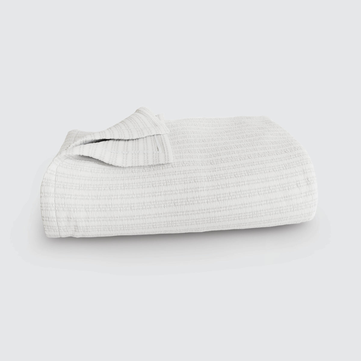 Image of a Bright White Everyday Cotton Coverlet folded up on a white background