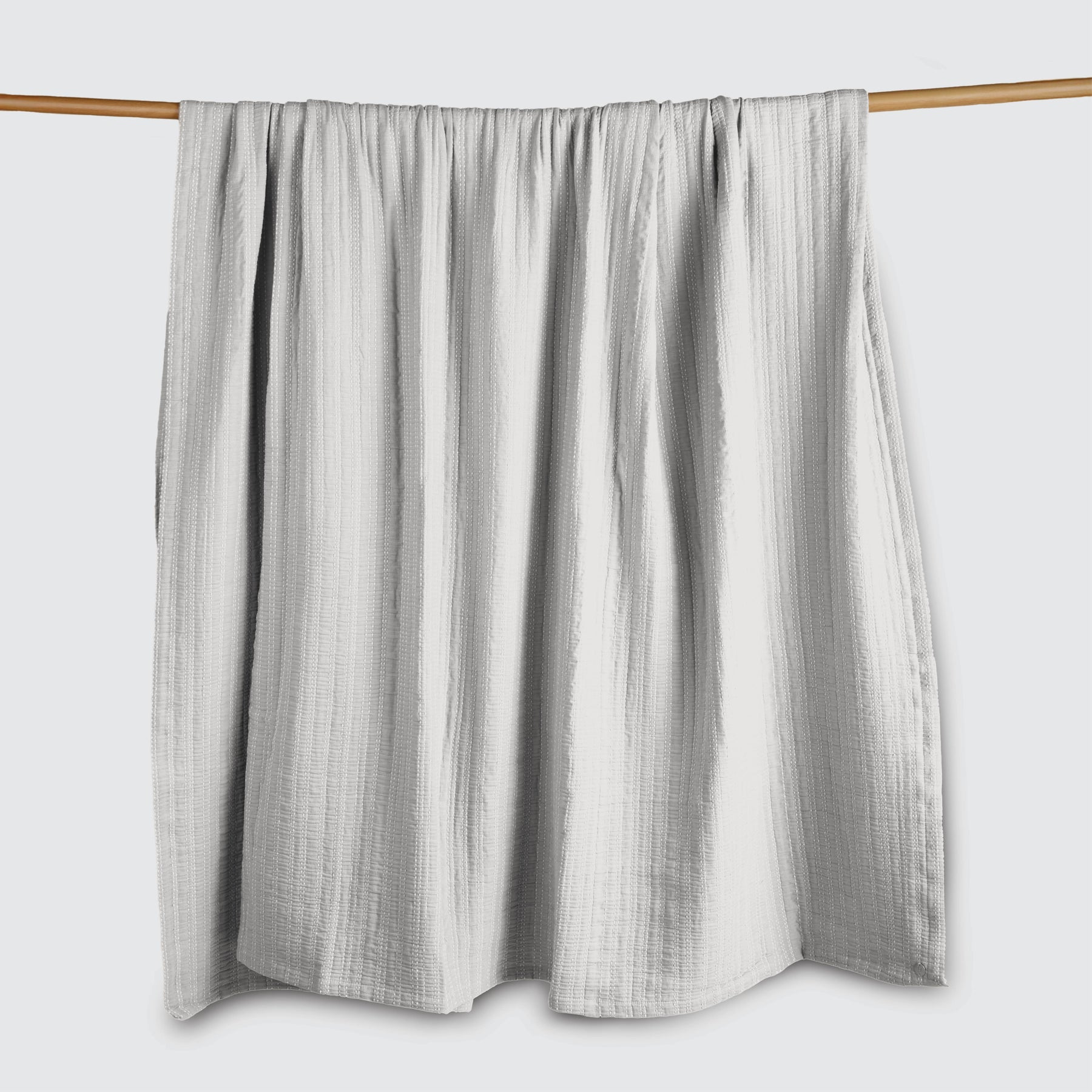 Image of a Bright White Everyday Cotton Coverlet hanging and draped over a wooden rod on a white background