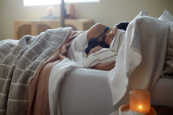 Image of woman laying on her side in bed with her head resting against the Chambered Down Pillow