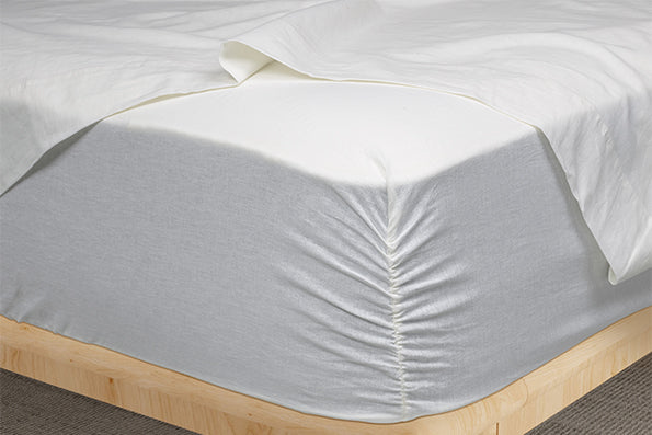 Image of White Blended Linen fitted sheet showcasing the Precision-Fit® Corner on the edge of a mattress