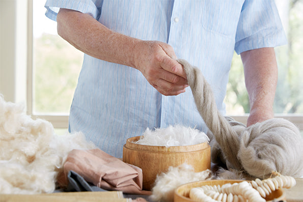 Image of Dr. Andrew Weil in a blue shirt feeling wool on a table with various other fabrics and materials