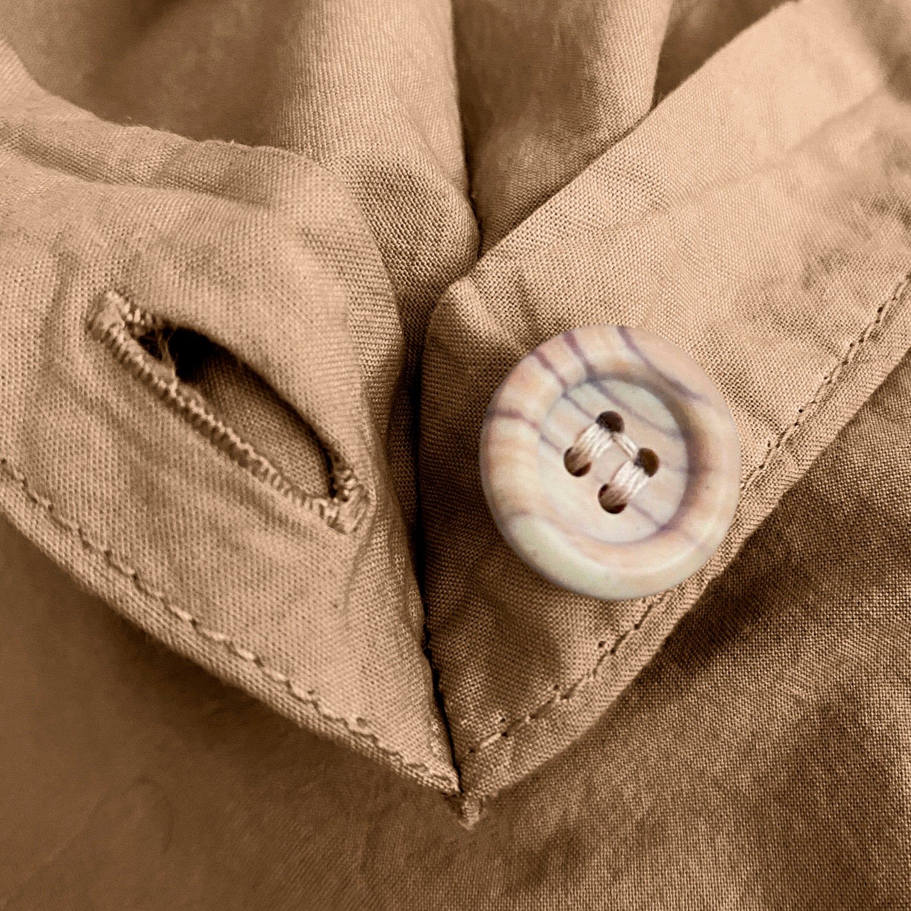 Close-up image of the button and button hole on the corner of an Ochre Garment Washed Percale Duvet Cover.