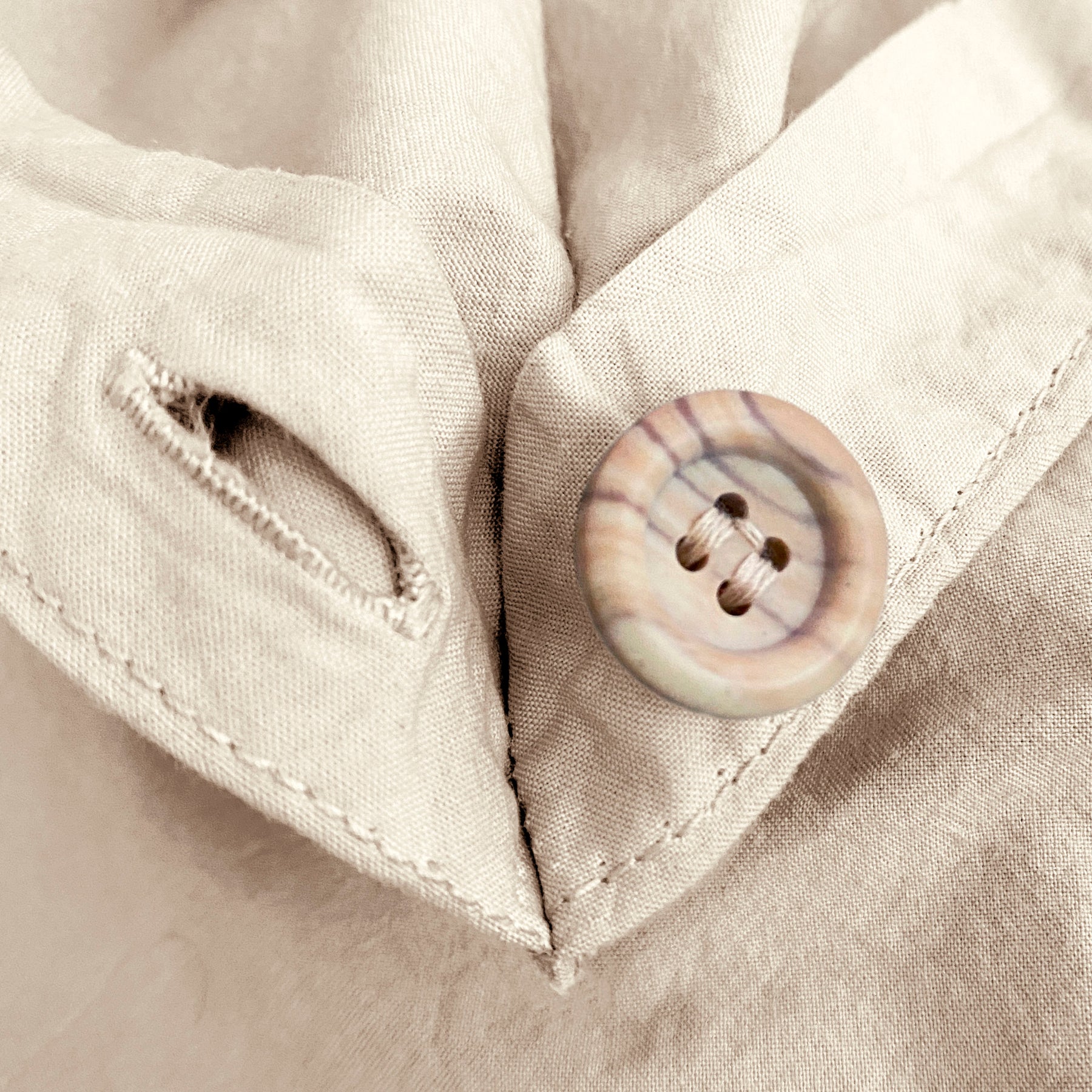 Close-up image of the button and button hole on the corner of an Ecru Garment Washed Percale Duvet Cover.