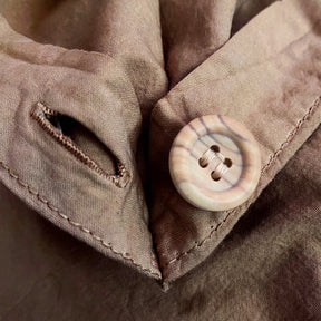 Close-up image of the button and button hole on the corner of a Desert Sand Garment Washed Percale Duvet Cover. 