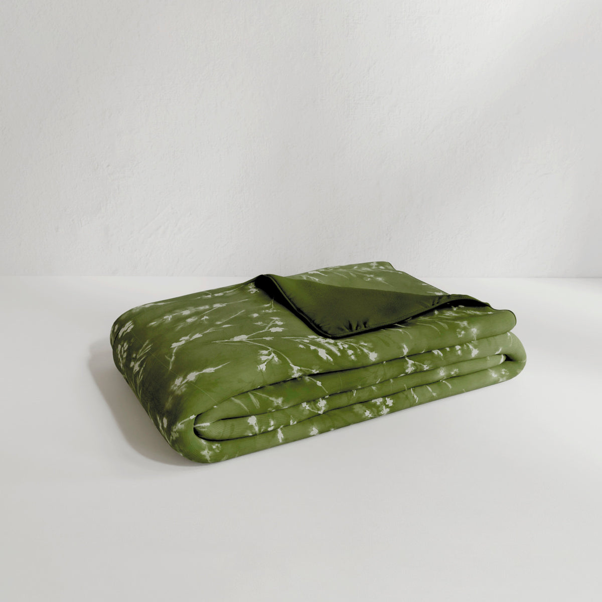 Image of the Floral Evergreen Duvet Cover + Cooling neatly folded with the floral side facing up and the back right corner folded over to show the reversible plain Evergreen side