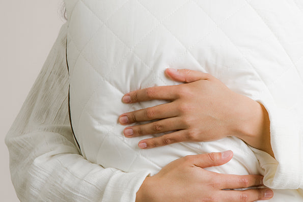 Image of person holding and hugging a white quilted pillow