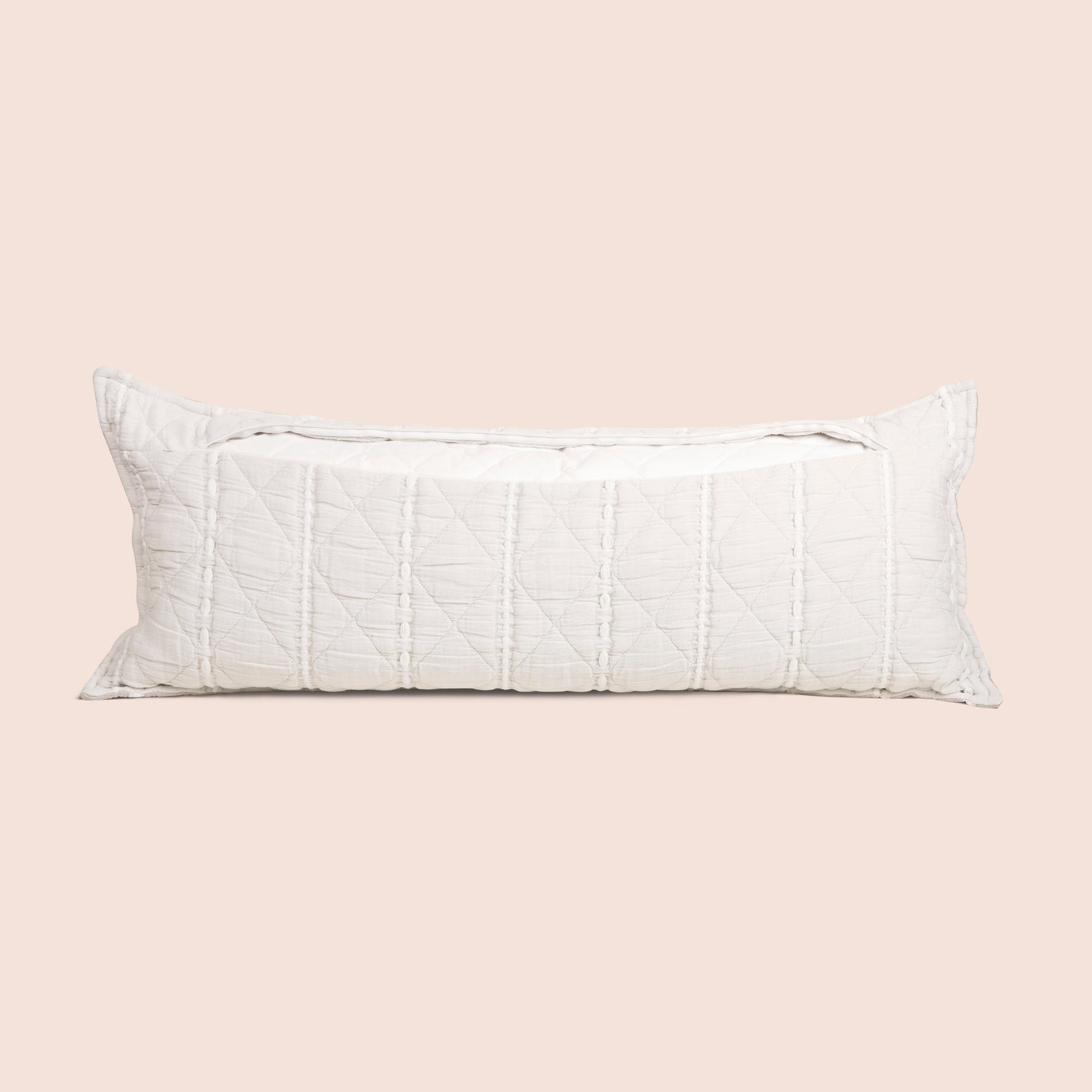Image of the back of the all-white reversible side of the Heritage Lumbar Pillow Cover on a lumbar pillow with the back zipper open on a light pink background