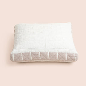 Image of the all-white side of the Heritage Meditation Cushion Cover on a meditation cushion with a light pink background