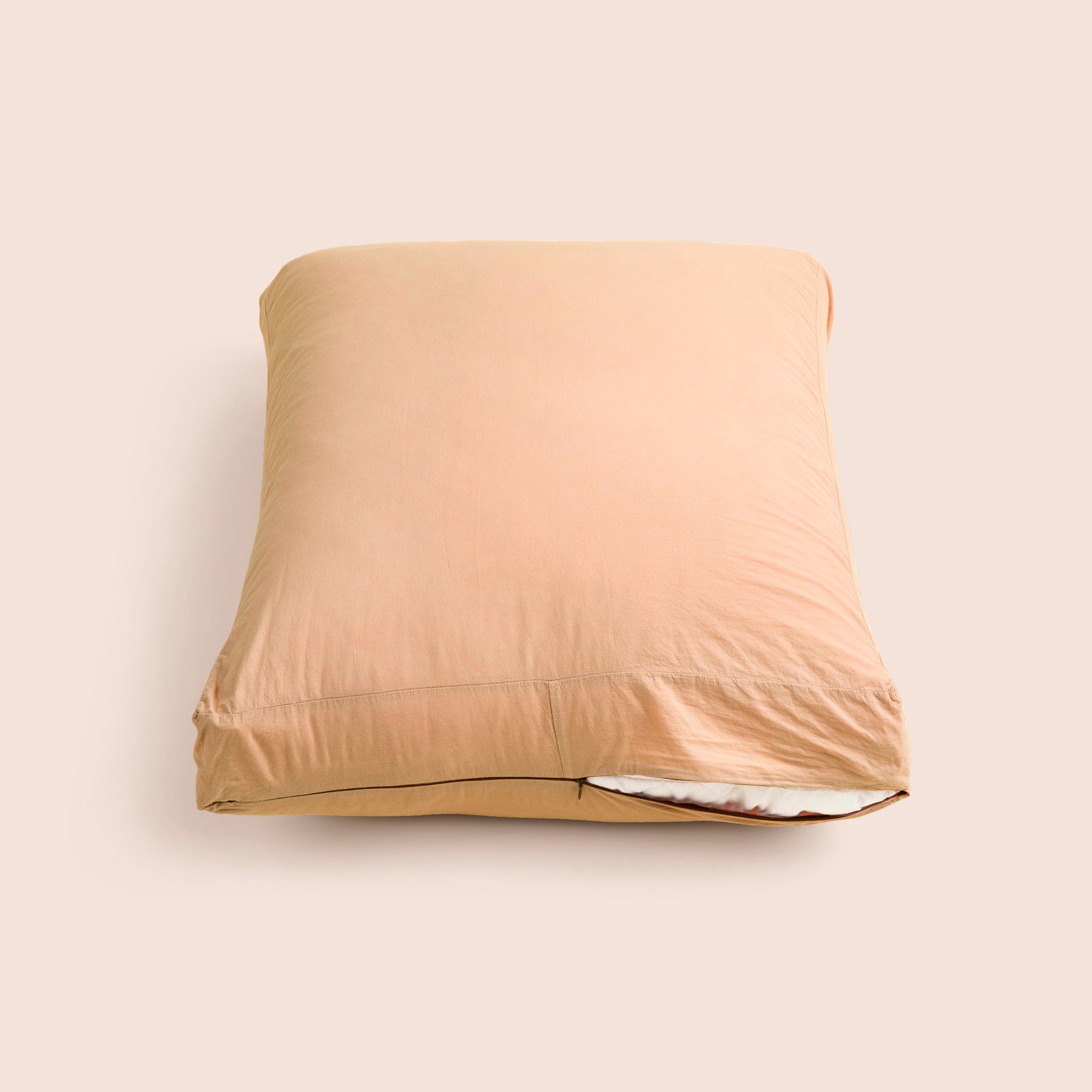 Image of Ochre Garment Washed Percale Meditation Cushion Cover showcasing a slightly opened zipper with a meditation cushion inside on a light pink background