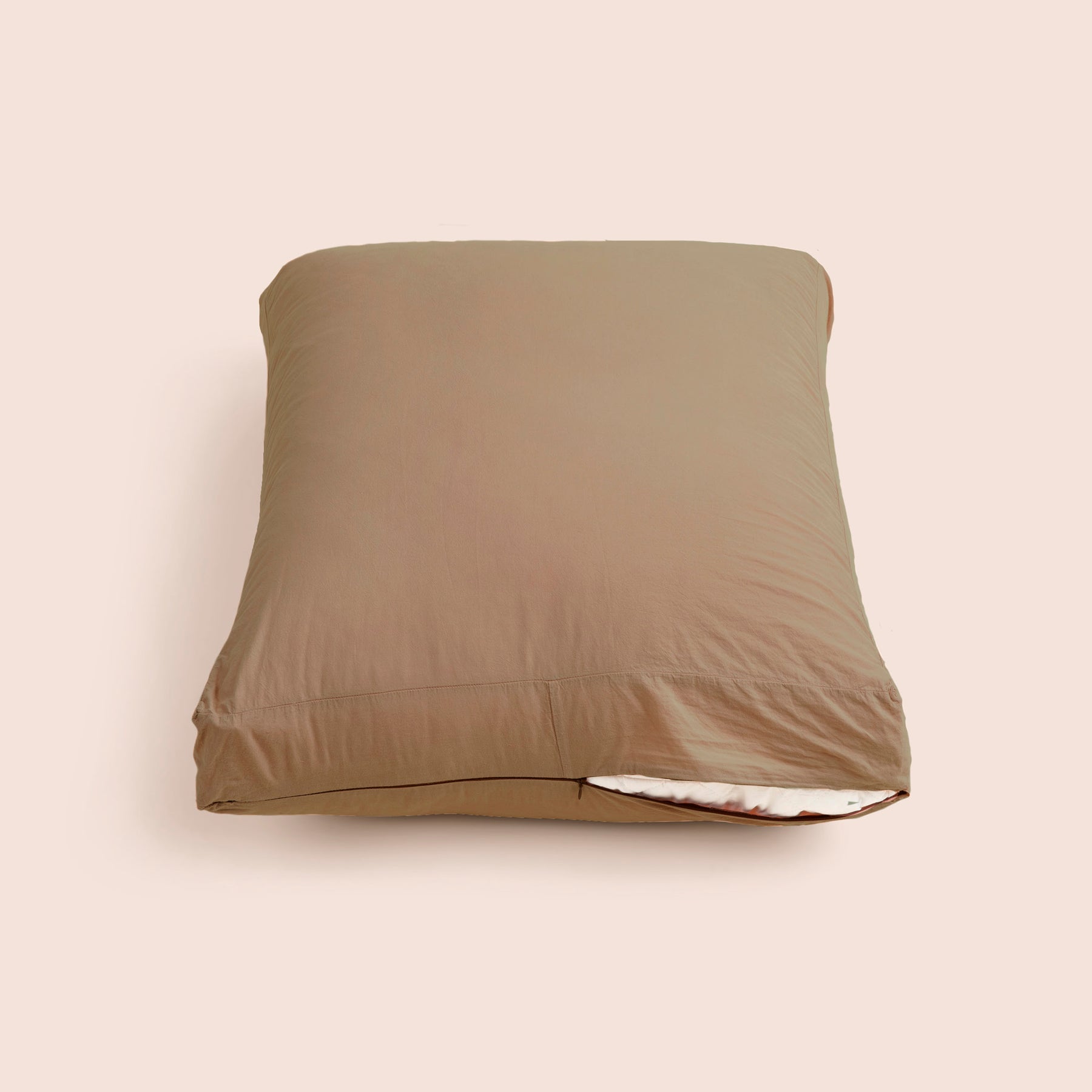 Image of Desert Sand Garment Washed Percale Meditation Cushion Cover showcasing a slightly opened zipper with a meditation cushion inside on a light pink background