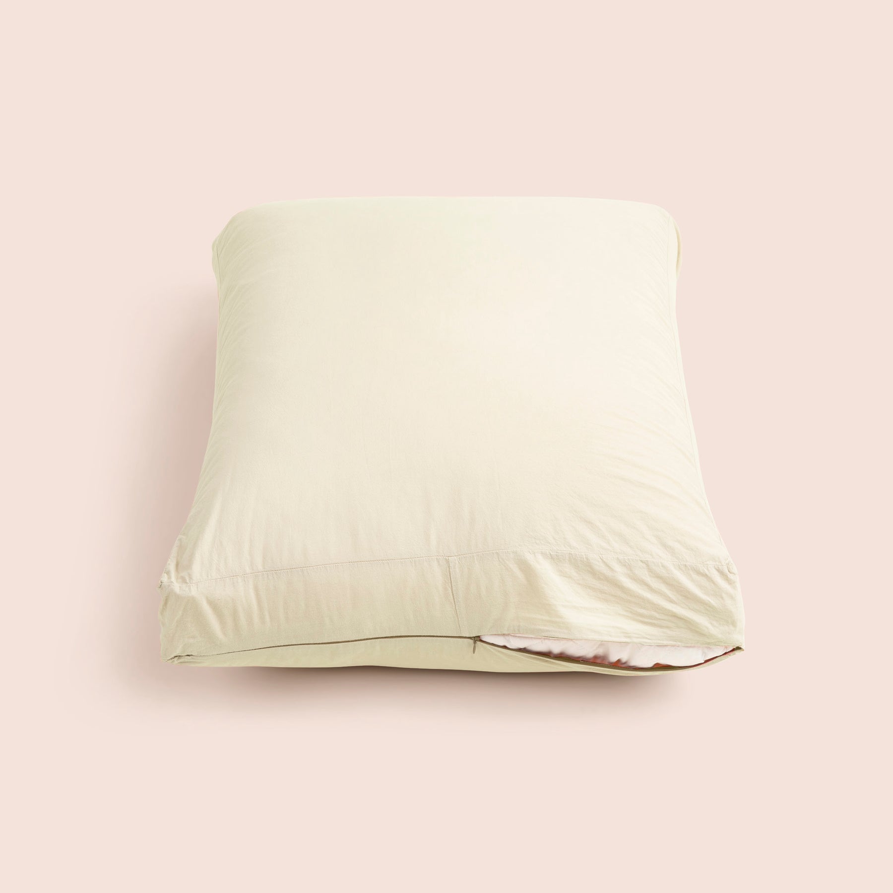 Image of Ecru Garment Washed Percale Meditation Cushion Cover showcasing a slightly opened zipper with a meditation cushion inside on a light pink background