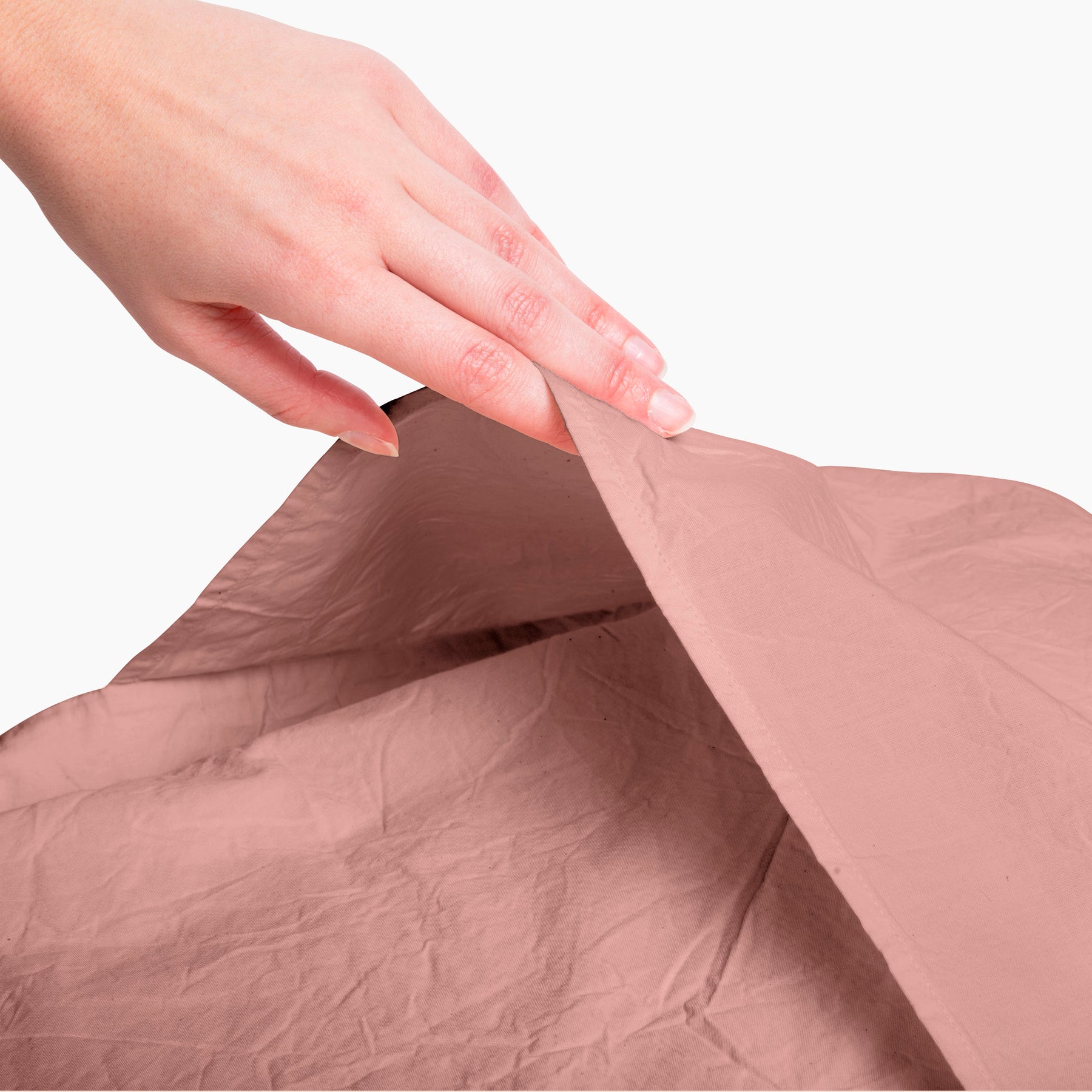 Image of a Pink Sandstone Garment Washed Percale Pillow Sham with a hand reaching down to open and showcase the enveloping design on the back