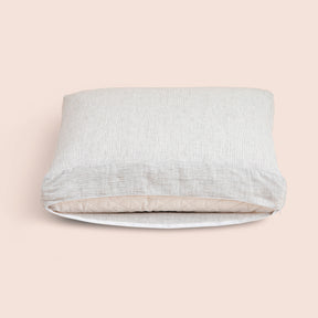 Image of the Pinstripe Relaxed Hemp Meditation Cushion Cover showcasing an opened zipper with a meditation cushion inside on a light pink background 