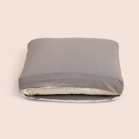 Image of the Stone Gray Relaxed Hemp Meditation Cushion Cover showcasing an opened zipper with a meditation cushion inside on a light pink background 