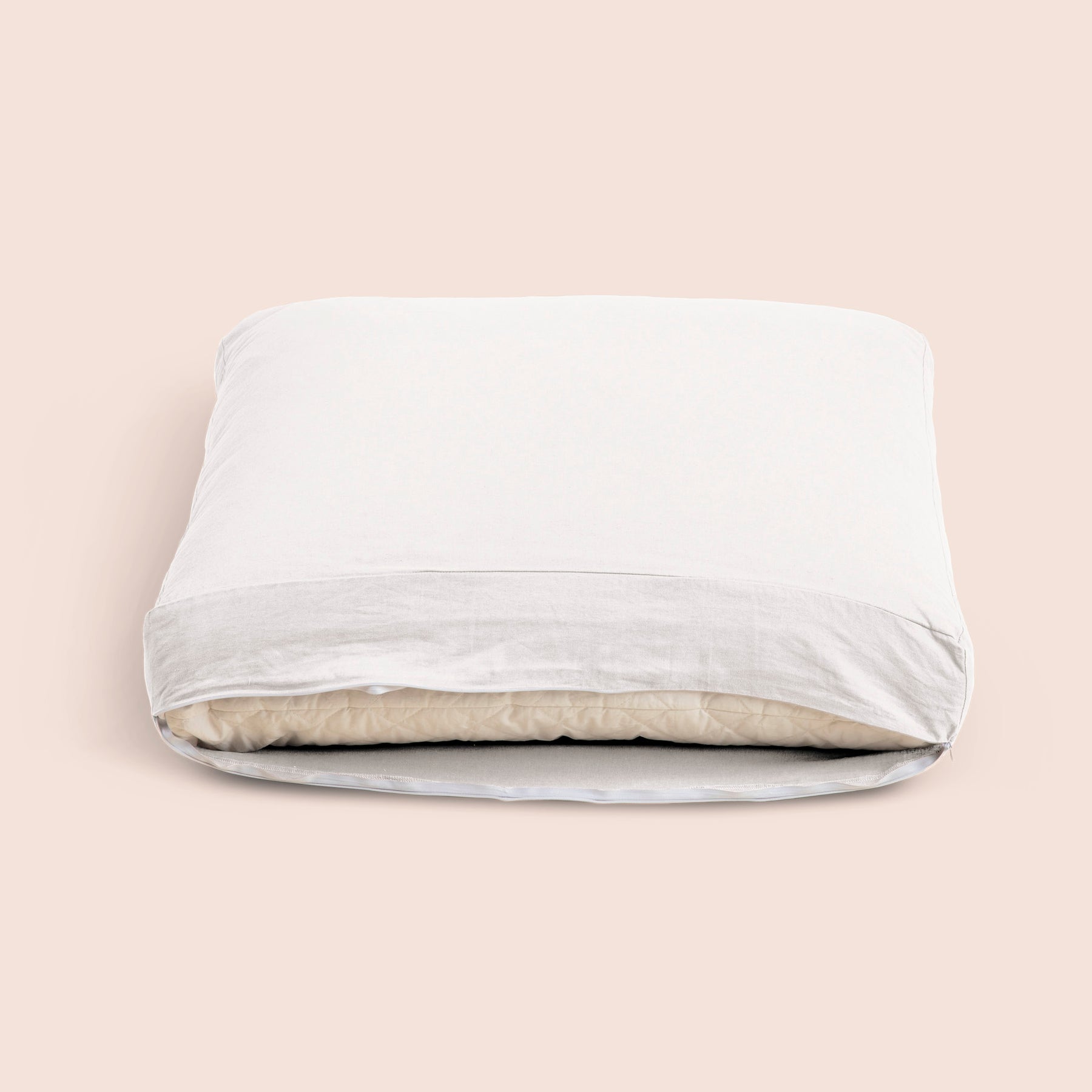 Image of the White Relaxed Hemp Meditation Cushion Cover showcasing an opened zipper with a meditation cushion inside on a light pink background 