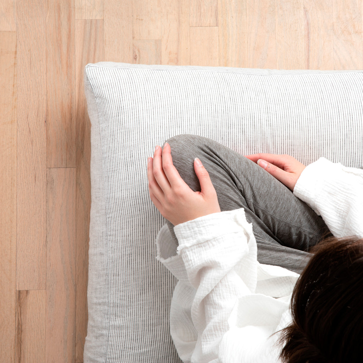 Image of woman sitting cross-legged on a meditation cushion with the Pinstripe Relaxed Hemp Meditation Cushion Cover