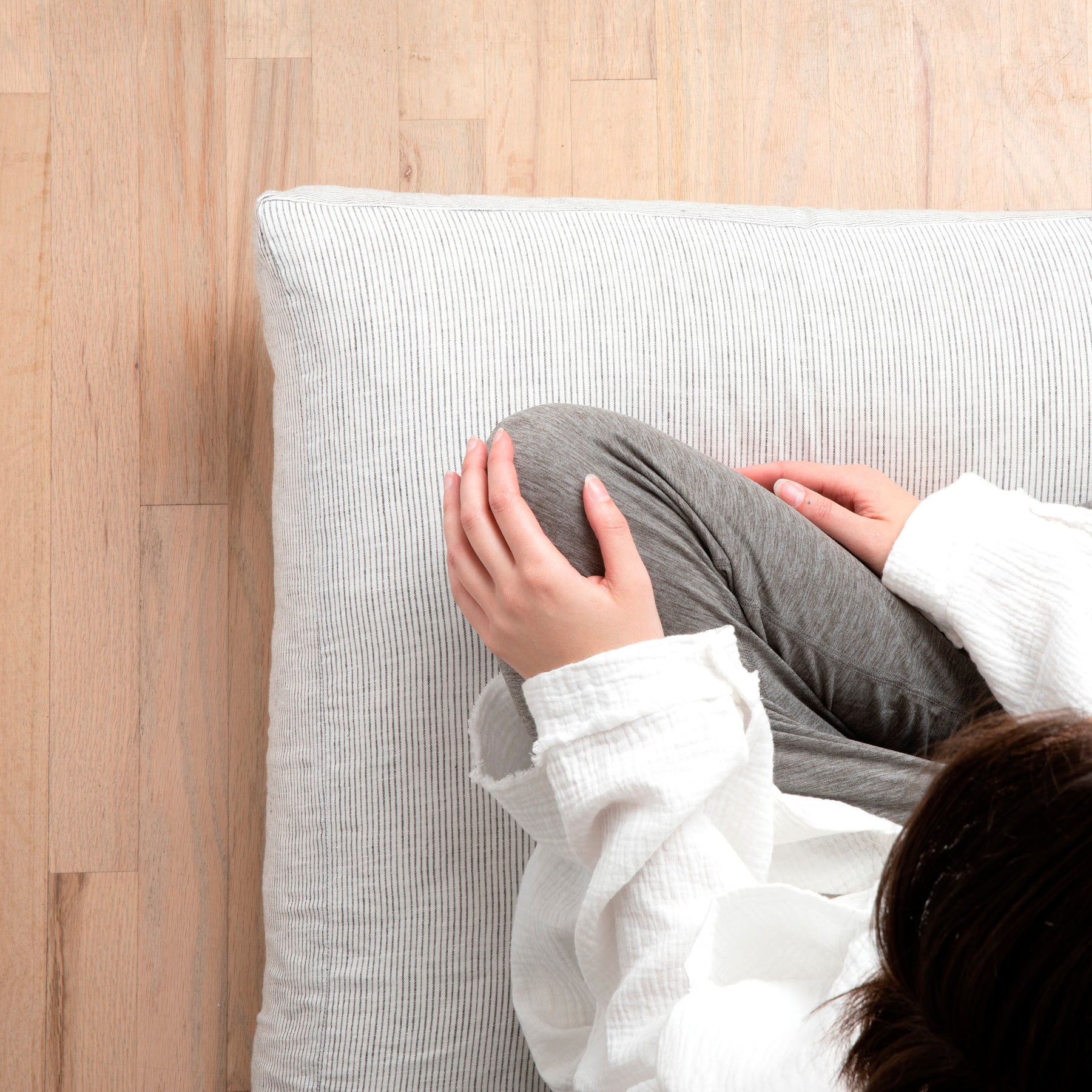 Image of woman sitting cross-legged on a meditation cushion with the Pinstripe Relaxed Hemp Meditation Cushion Cover 