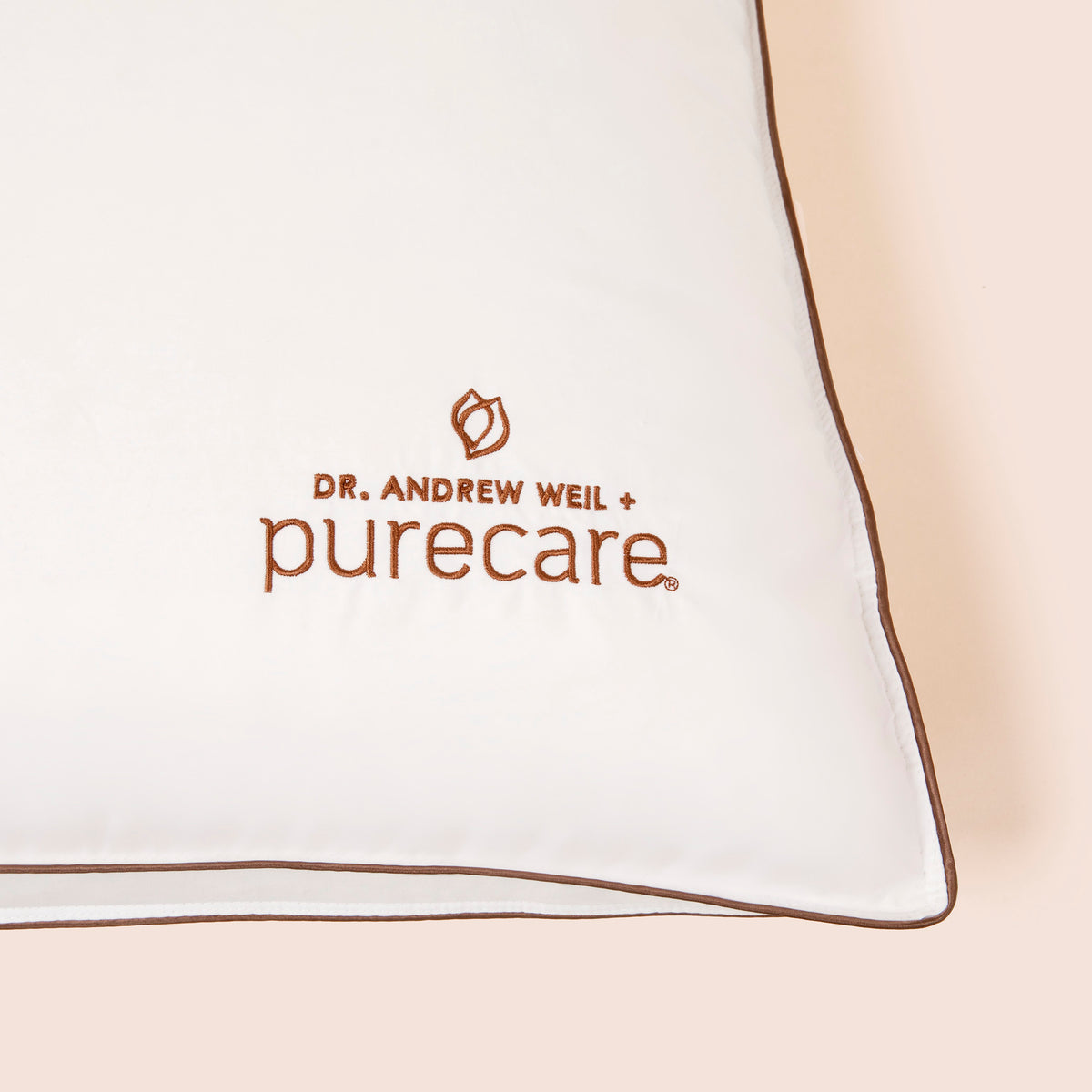 Close-up image of the Dr. Andrew Weil + Purecare logo on bottom right corner of Chambered Down Pillow