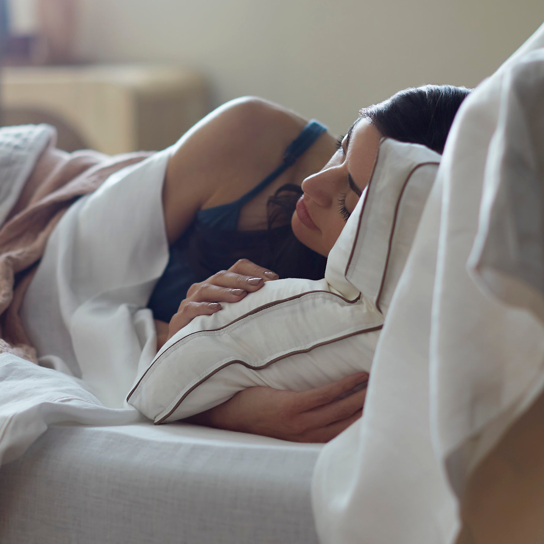 Woman laying on her side in bed sleeping on the Chambered Down Pillow