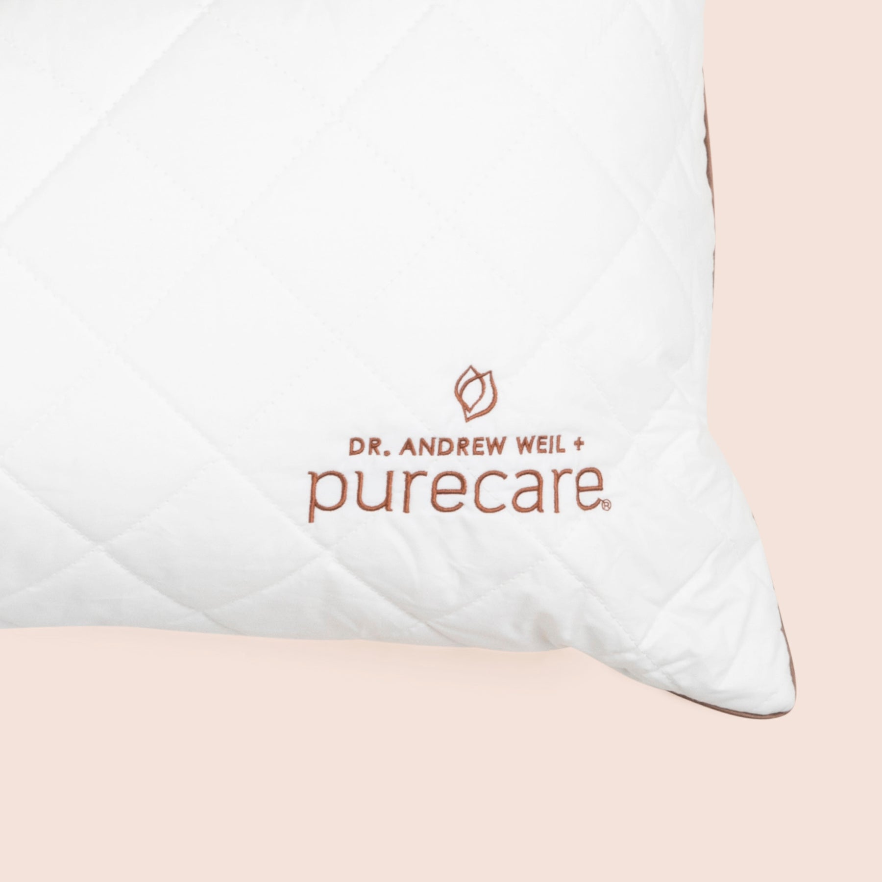Close-up image of the Dr. Andrew Weil + Purecare logo on bottom right corner of pillow