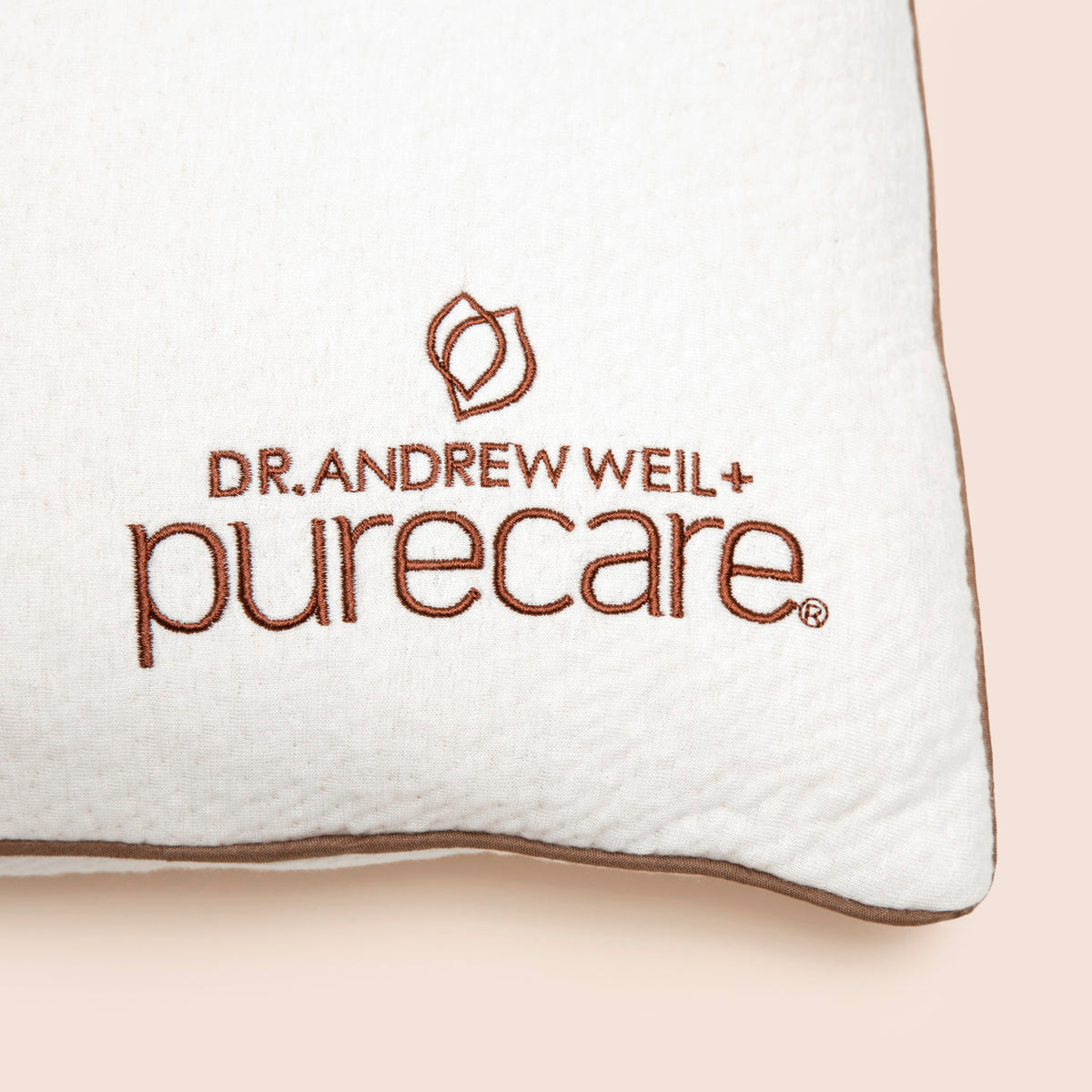 Close-up image of the Dr. Andrew Weil + Purecare logo on bottom right corner of pillow