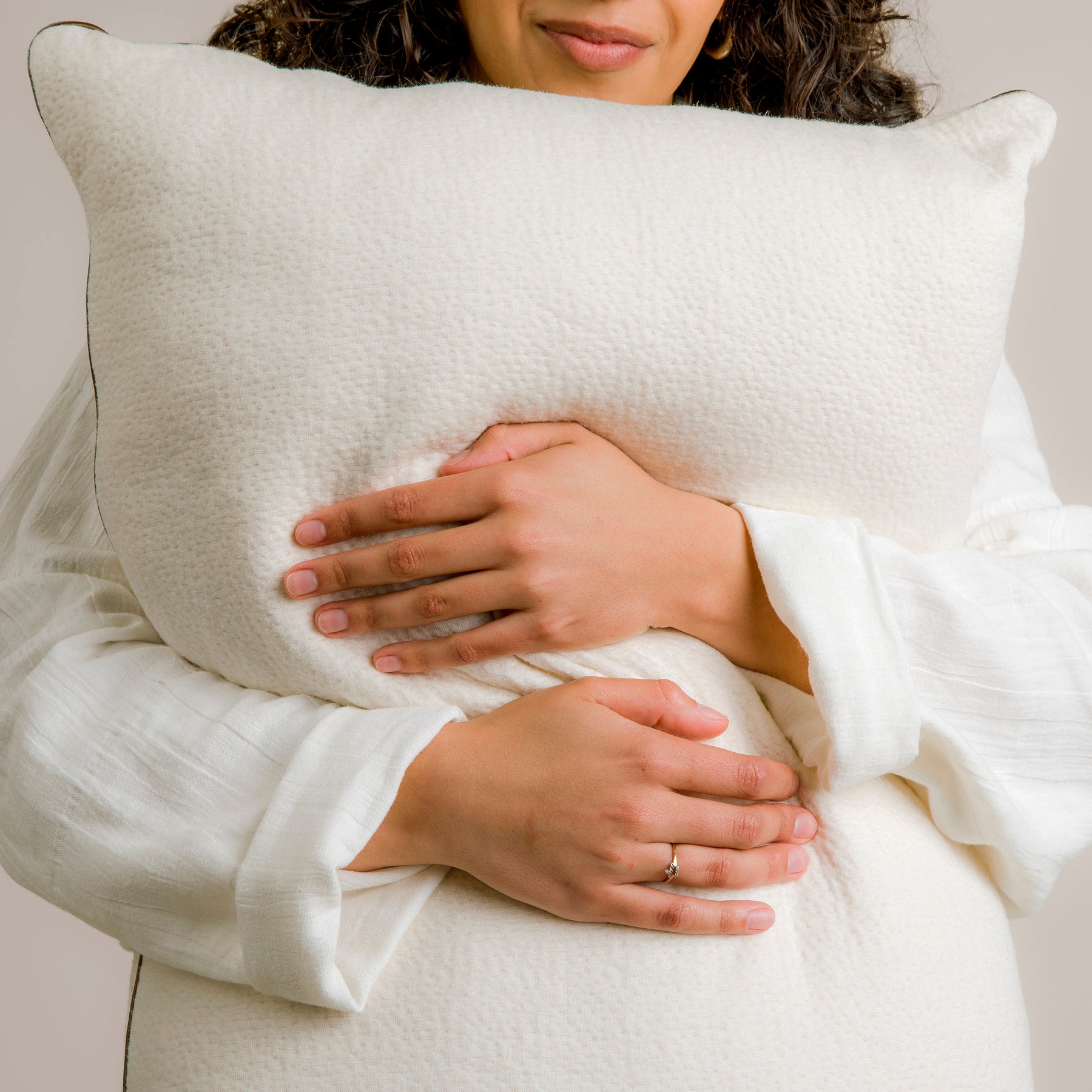 Image of smiling woman in white robe hugging the Perfect Kapok Pillow