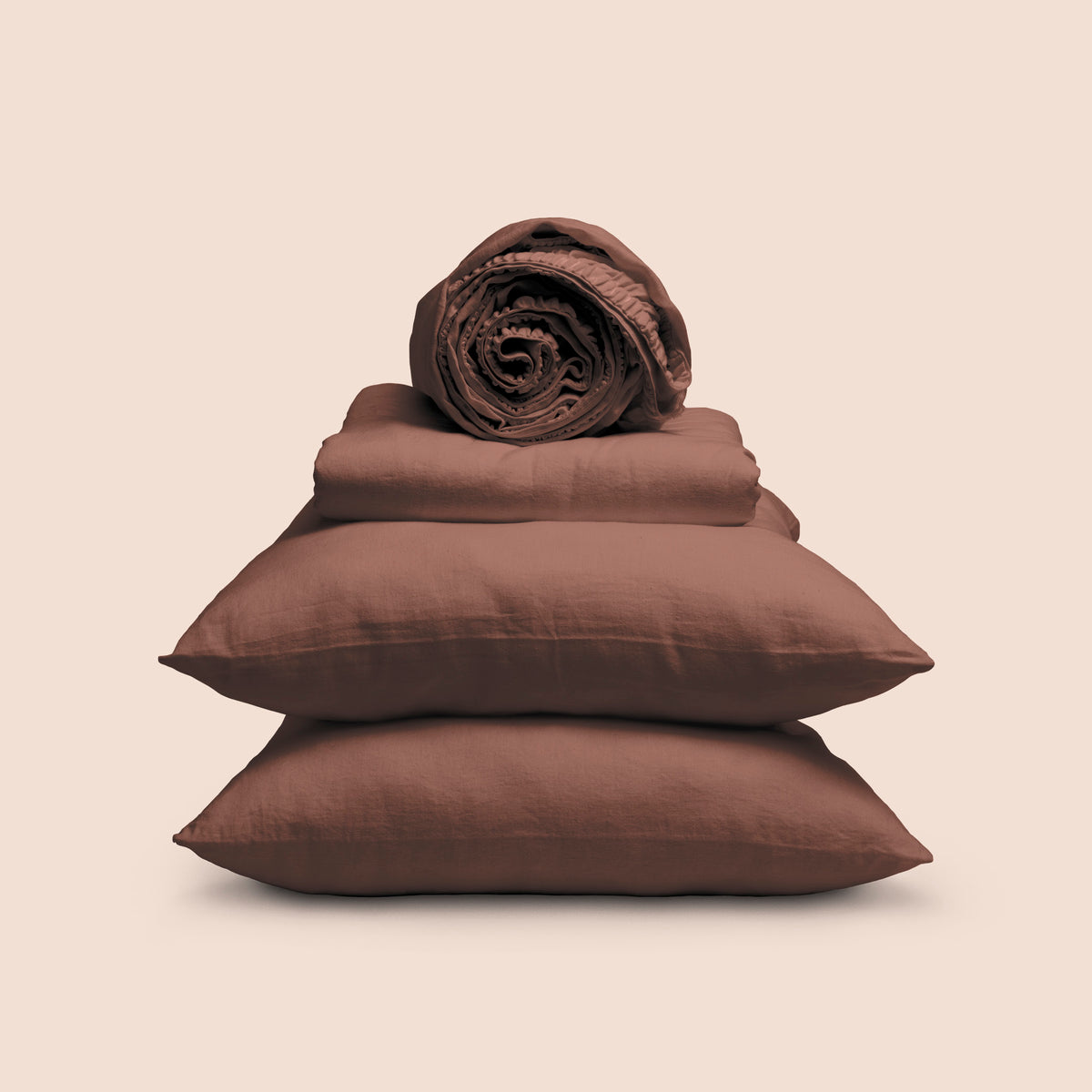 Image showcasing entire Cacao Blended Linen Sheet Set on a light pink background. Set features a rolled-up fitted sheet on top, a neatly folded flat sheet, and two stacked pillowcases. 