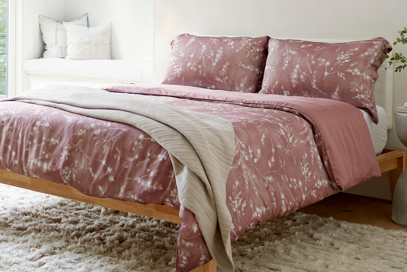 Image of a bed in a white room with the Floral Ash Rose Duvet Cover/Pillow Shams and an Oatmeal Everyday Cotton Coverlet at the foot of the bed