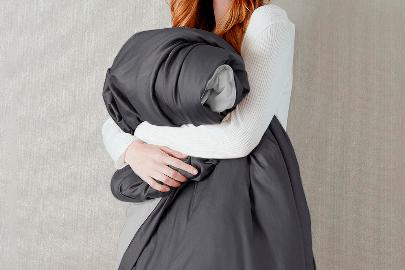 Image of a woman dressed in white holding a Shadow/Dove Gray Duvet Cover against her