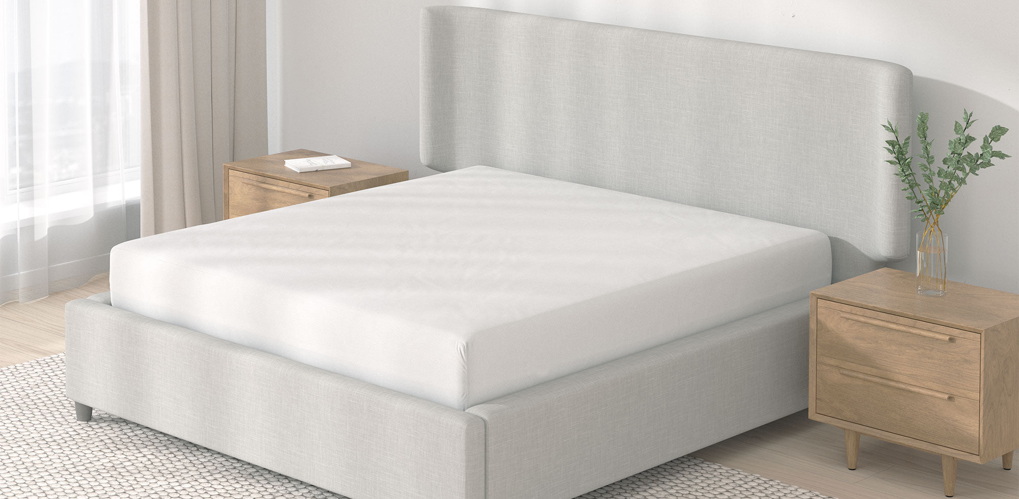 Image of an undressed bed with just a Mattress Protector on it in a light neutral room