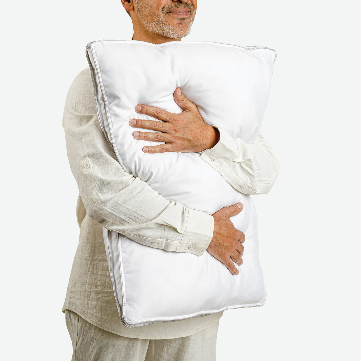 Image of a smiling man facing slightly to the right and hugging the Cooling Fiber Pillow against him