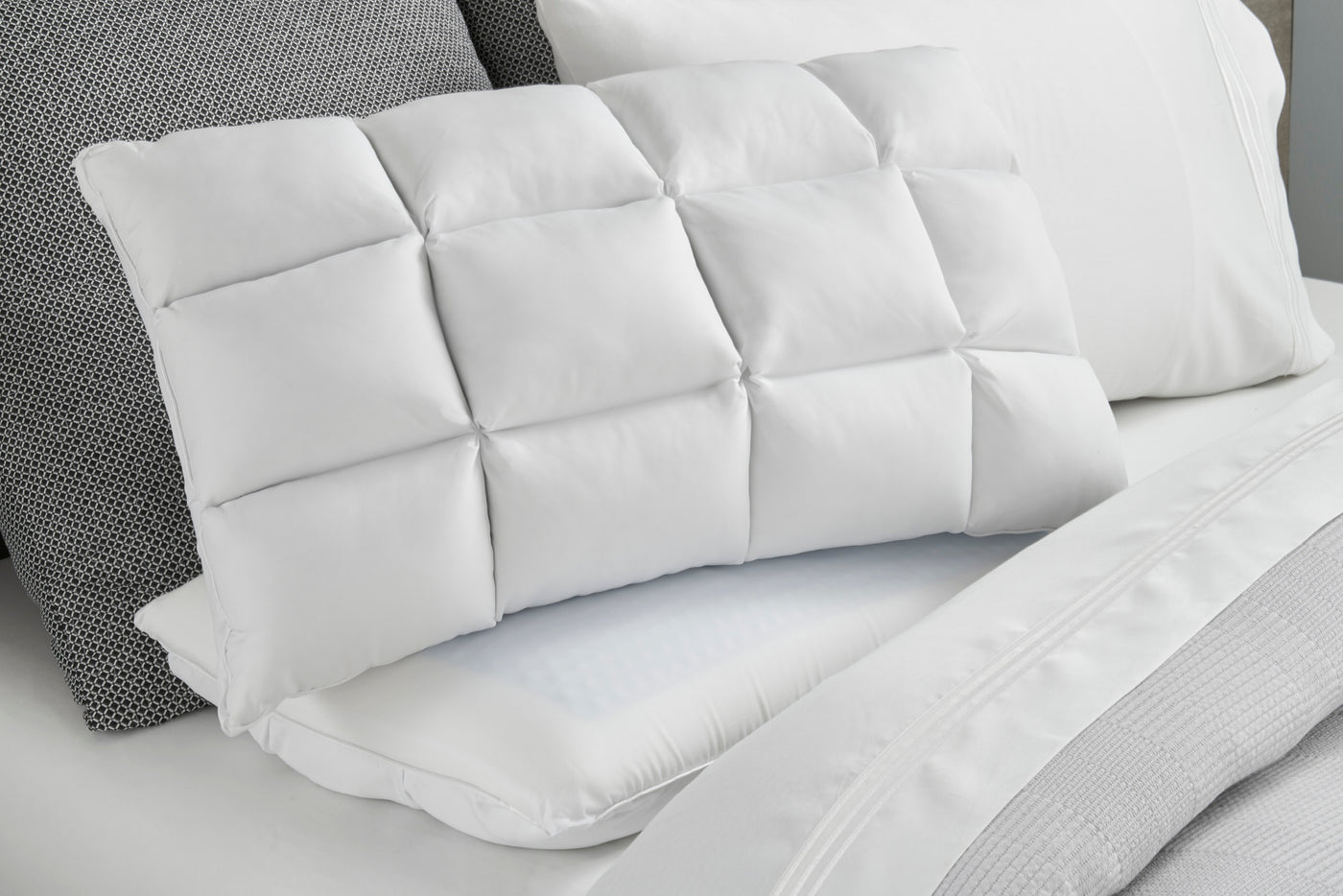 Image of a Cooling SoftCell® Chill Pillow on a gray and white bed with the SoftCell side facing forward