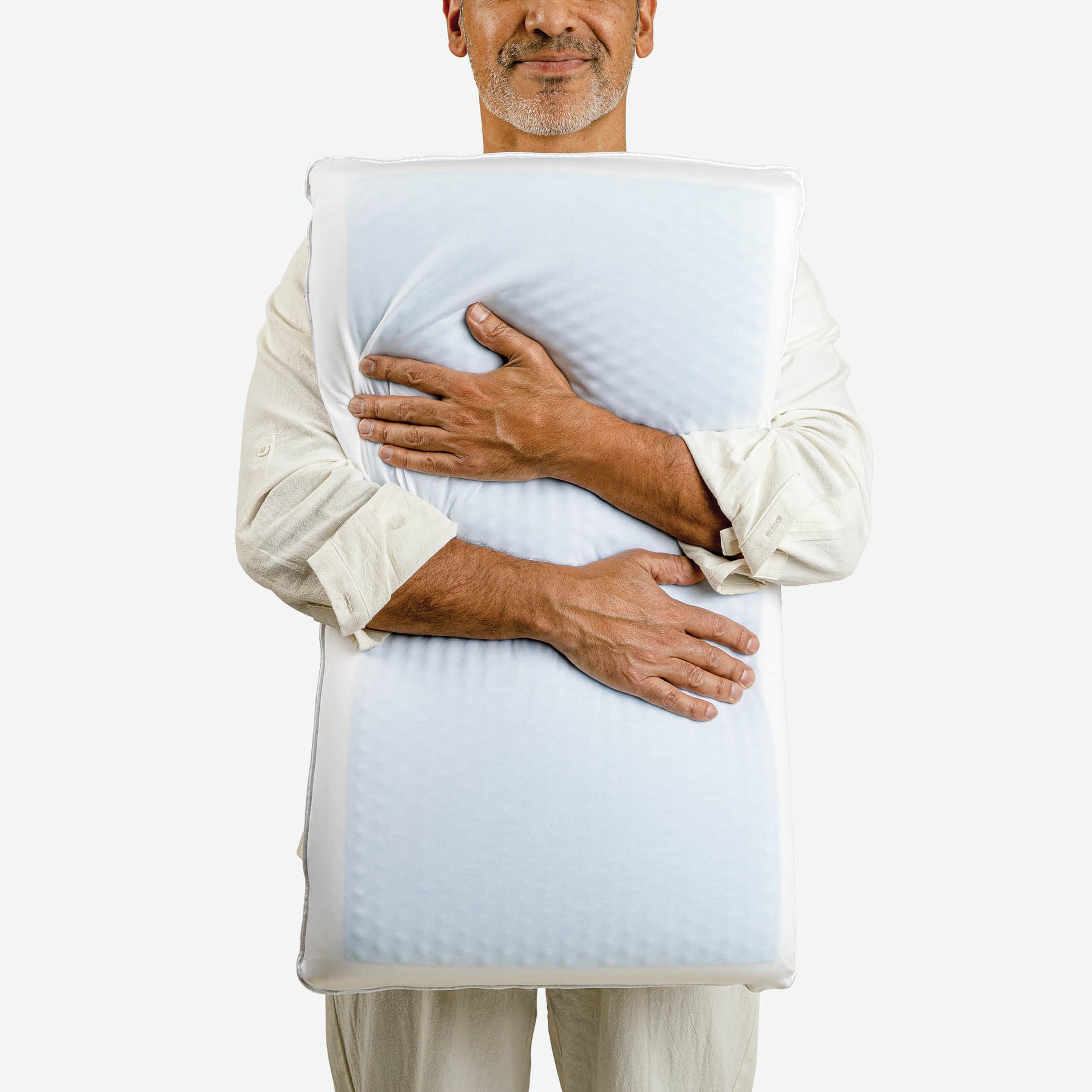 Image of a man smiling and hugging the Cooling Replenish Pillow against his chest with the cool gel side facing forward