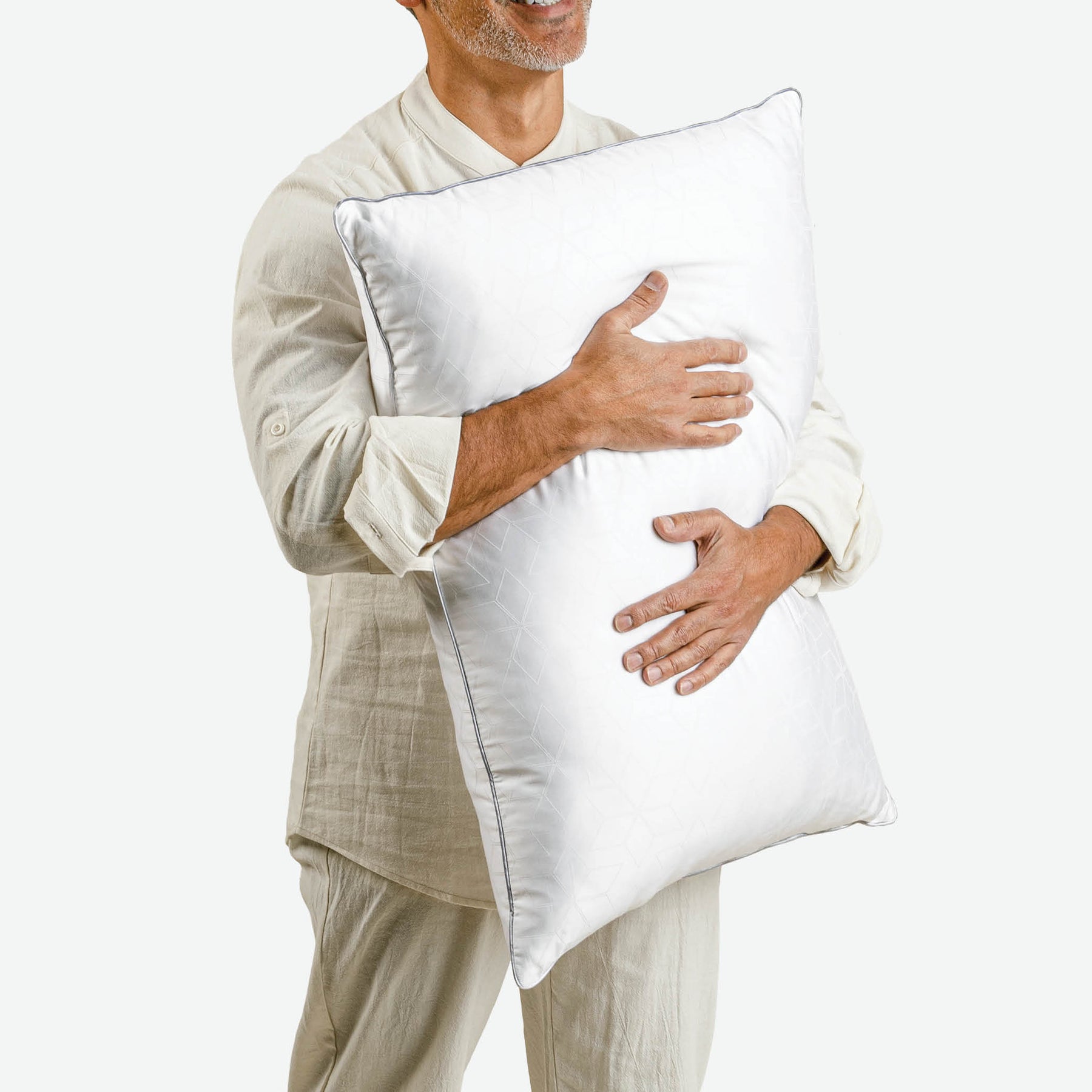 Image of a smiling man turned slightly to the right and hugging the Cooling Shattered Ice Pillow towards his chest
