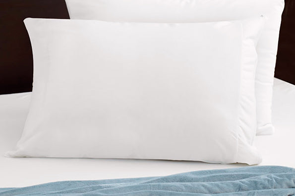 Image of two pillows with white pillow protectors placed standing up on a bed with a white sheet and a light blue blanket