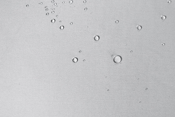 Close-up image of white protector fabric with water droplets across the top and right side