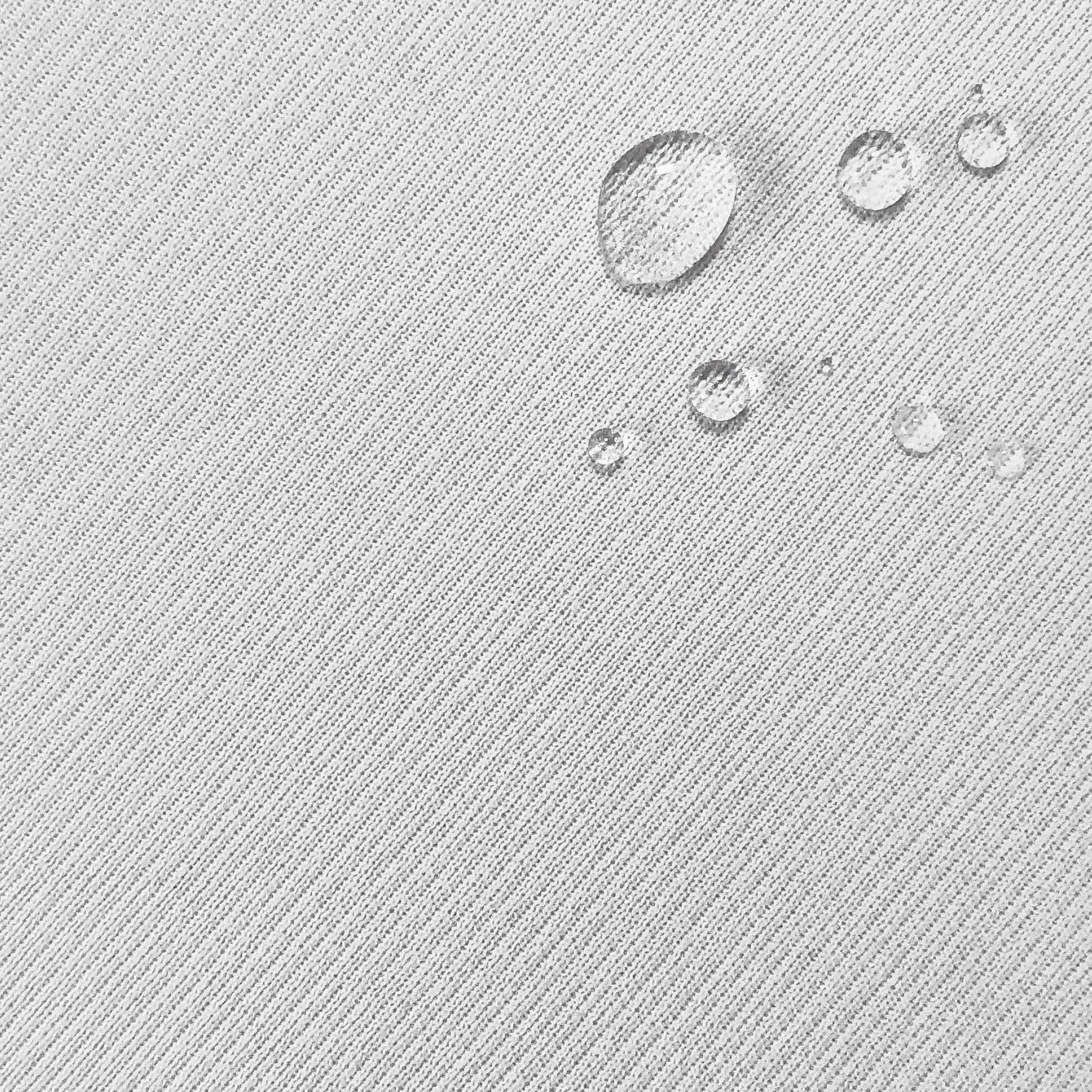 Close-up image of the white mattress protector fabric with water droplets in the top right corner