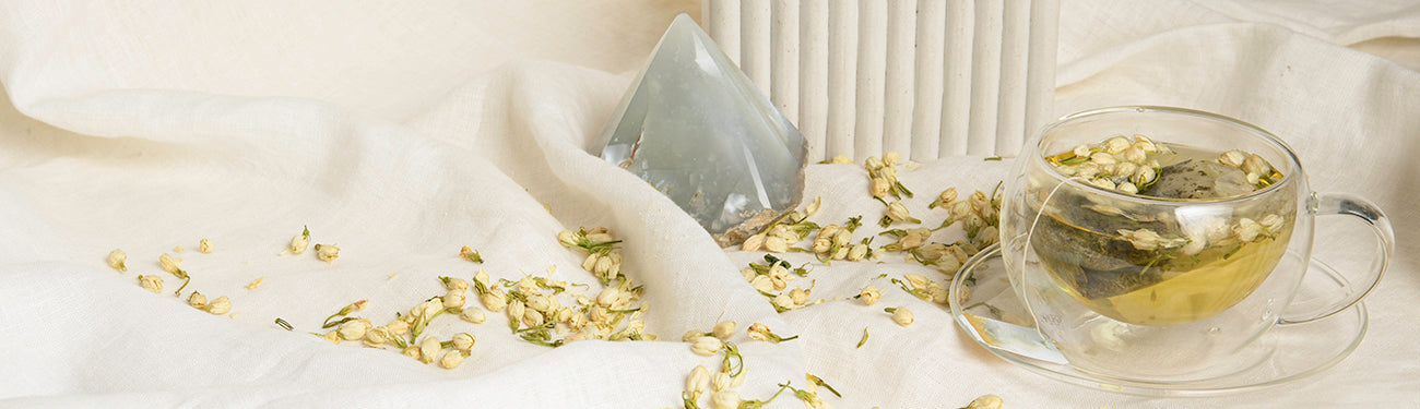 Image of jasmine flowers by a cup of tea and a crystal