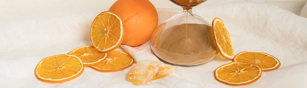 Image of orange slices by an hourglass on white fabric