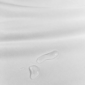 Close-up image of the white mattress protector fabric with water droplets in the bottom center