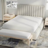 Image of a bed in a neutral colored room with just a white Cooling 5-Sided Mattress Protector on the bed