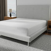 Image of a mattress protector on a bed with a gray headboard