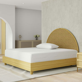 Image of a yellow-colored bed with just a mattress protector and pillow with pillow protector on the bed. The bed is in a light, neutral-colored room with slight yellow accents and vased Jasmine flowers to the left side.