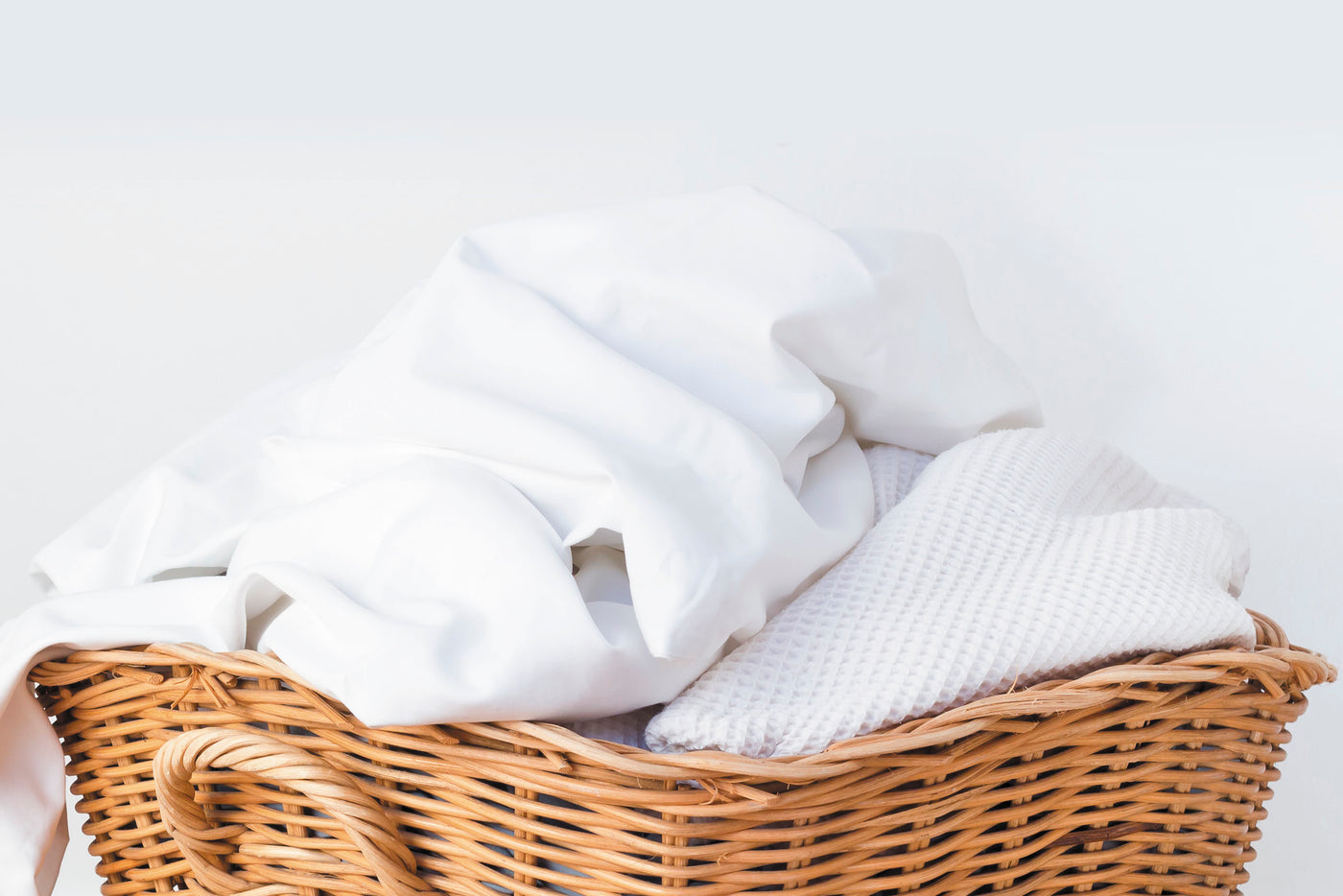 Image of a basket with various white fabrics in it on a white background