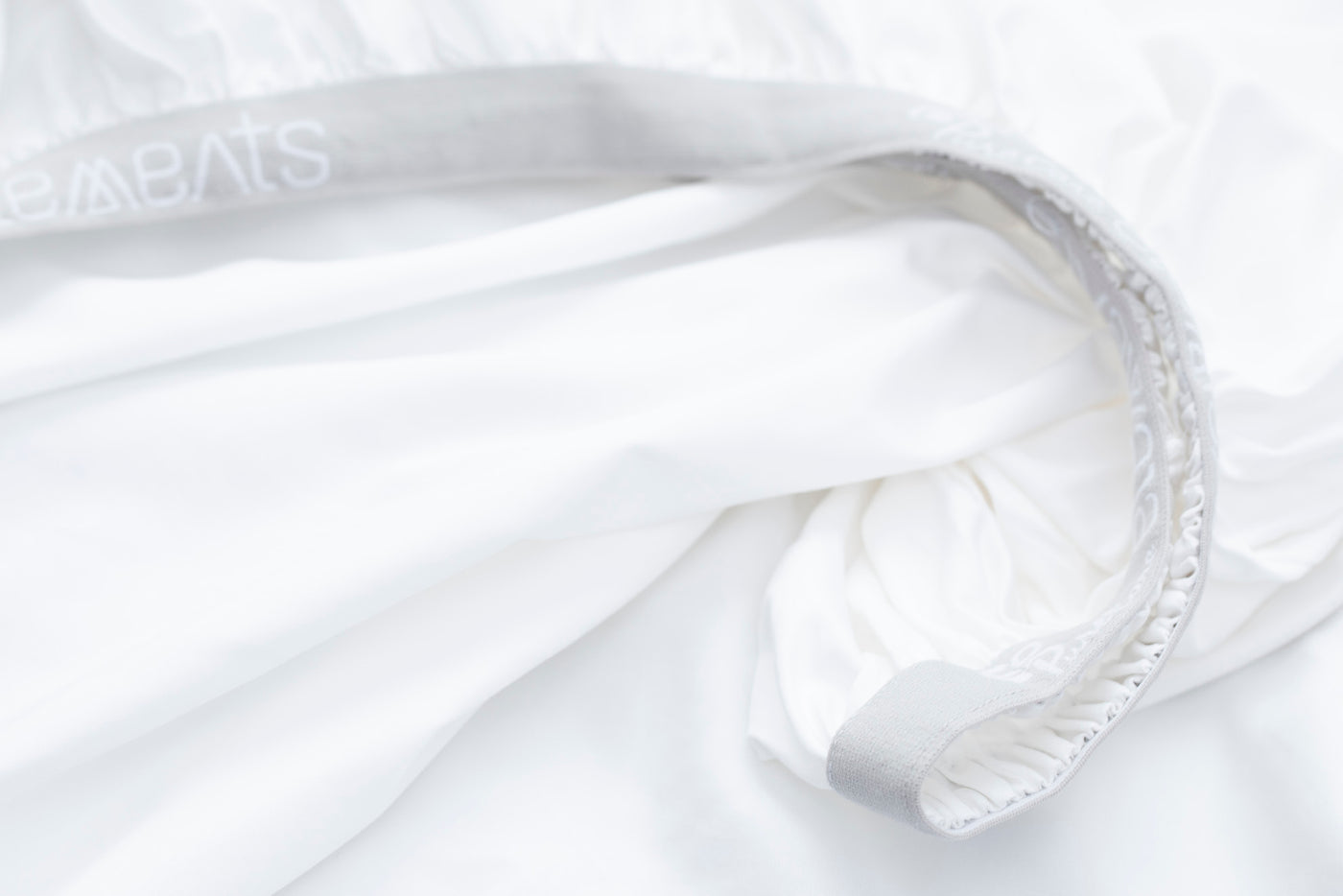 Image of a white fitted sheet showcasing the 1" elastic cuff on the bottom
