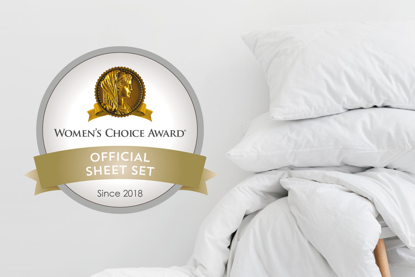 Image of a pile of white bedding on a wooden stool to the right side against a white wall with a large sticker on the left side that says: "Women's Choice Award Official Sheet Set Since 2018"